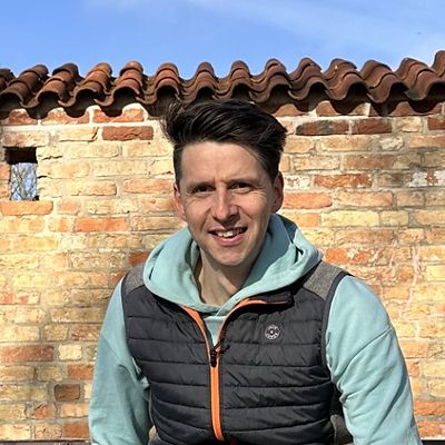 Jan Tauer, Initiator von freundwärts, sitzt auf einer Parkbank vor einer Backsteinmauer
